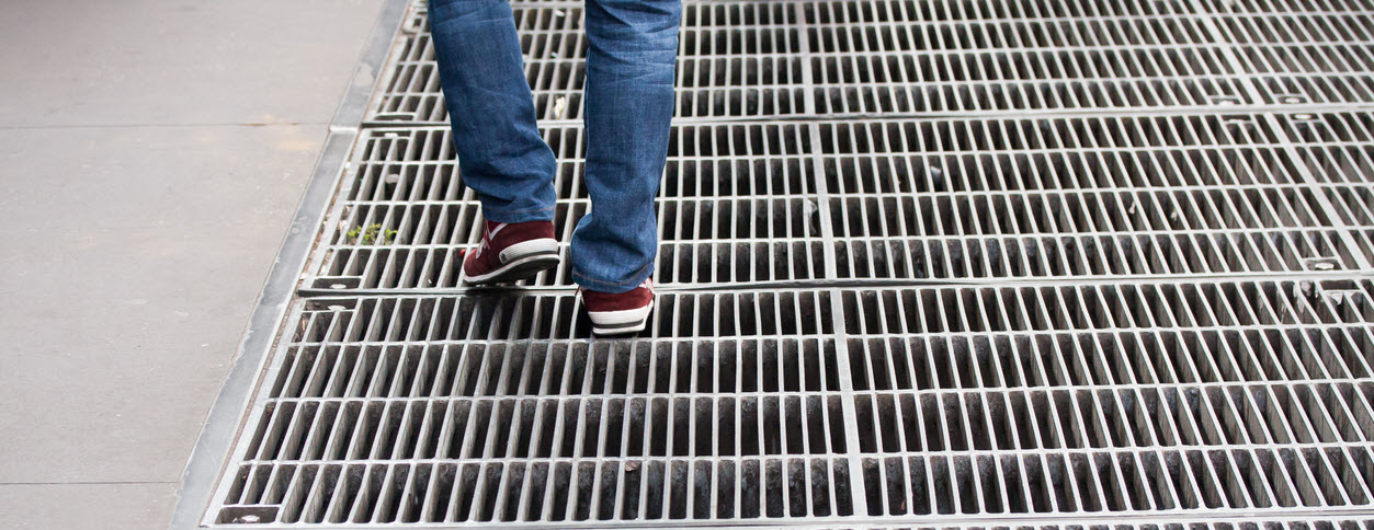 How does sidewalk grating improve drainage in urban walkways?